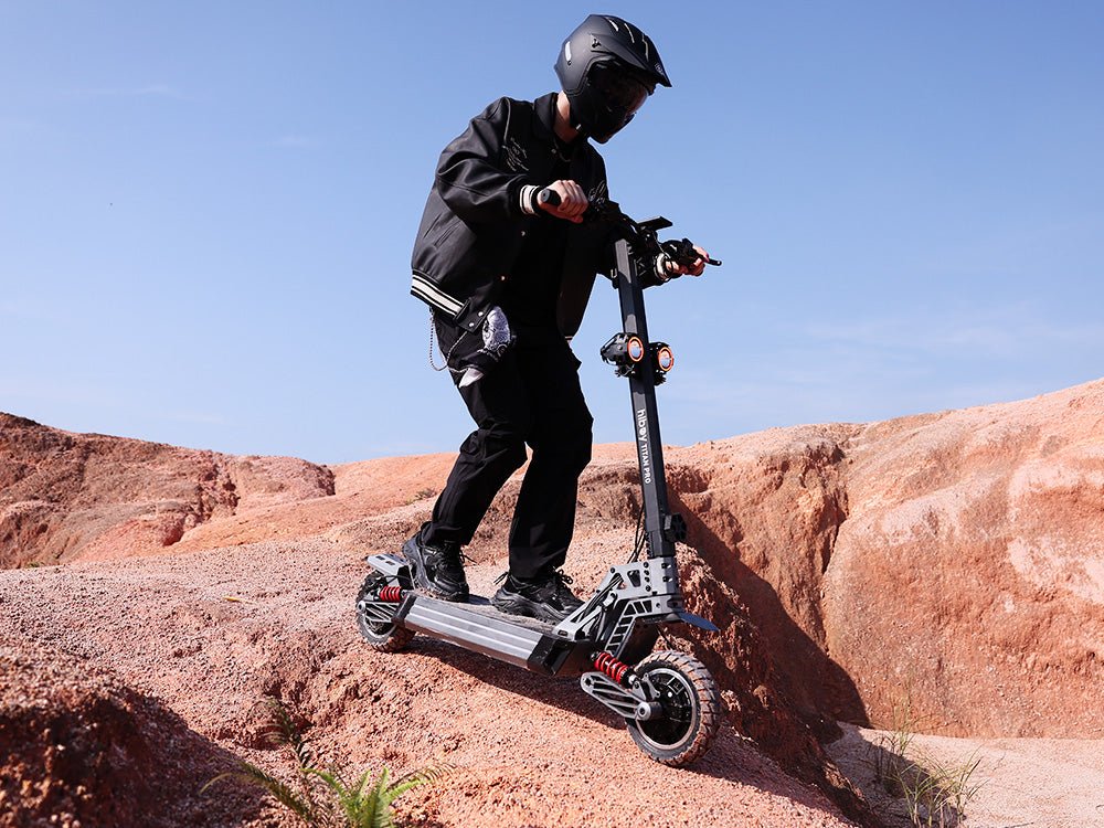 Rider taking a Hiboy TITAN PRO electric scooter over bare rock, both coil-over shocks compressed