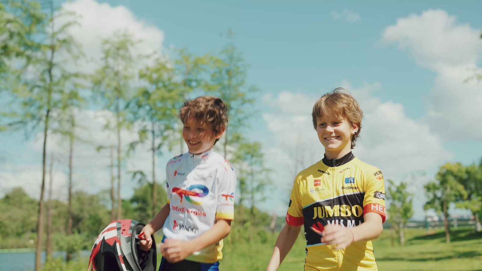 Two children in a grassy field with an adult standing behind them, one child seated on a Hiboy DK2 electric dirt bike