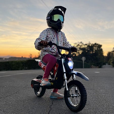 A child riding a Hiboy DK1 electric dirt bike along a track at sunset