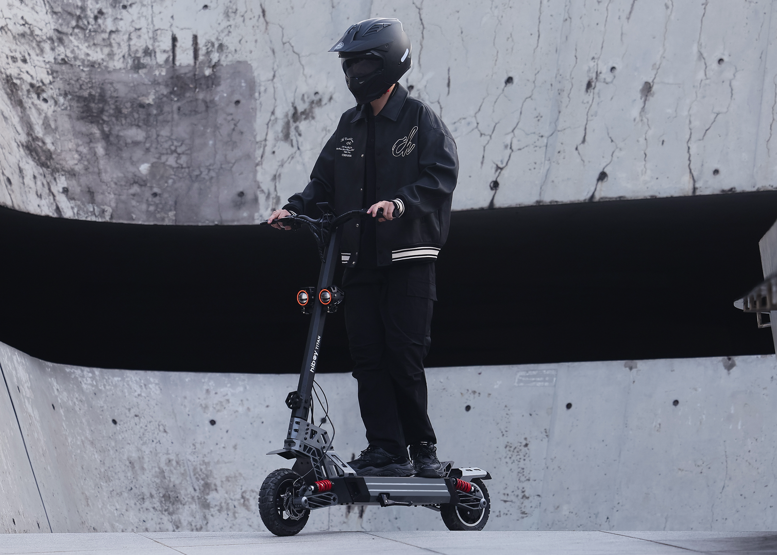 Rider taking a Hiboy TITAN electric scooter down a concrete ramp, both coil-over shocks loaded