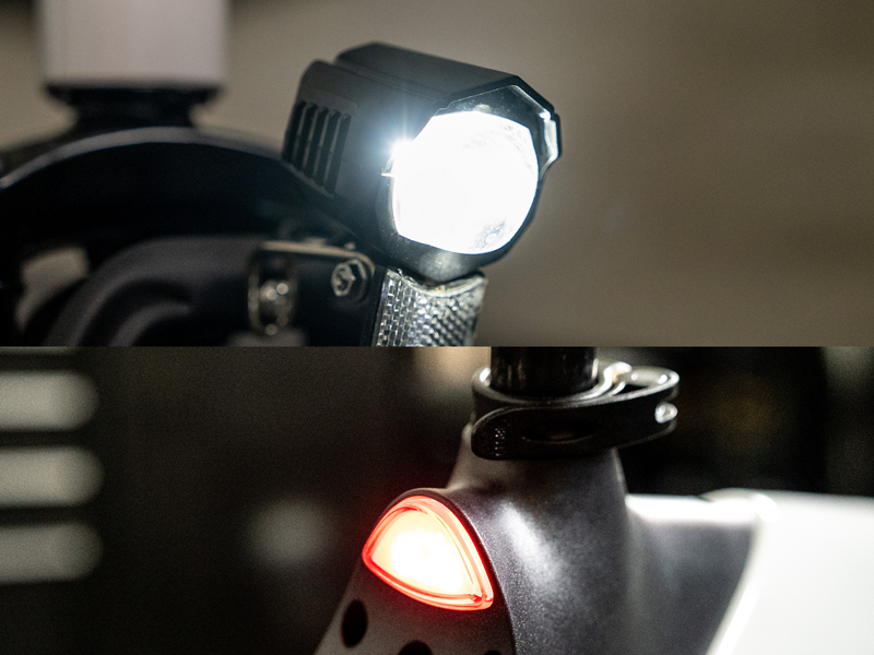 The Hiboy C1 headlight lit, with the red rear light glowing behind it