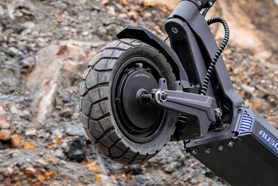 Deep-tread rear tire and hub motor of the Ausom DT2 Pro electric scooter on rocky ground