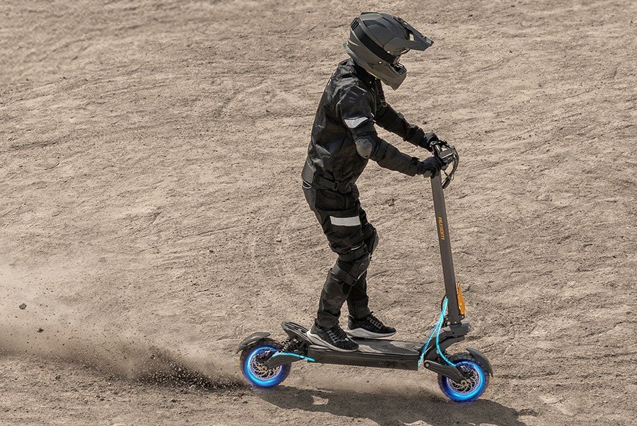 Rider braking the Ausom F1 Max electric scooter into a controlled slide on packed dirt