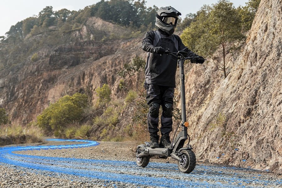Helmeted rider on the Ausom L2 Max dual motor e-scooter following a winding gravel road along a hillside