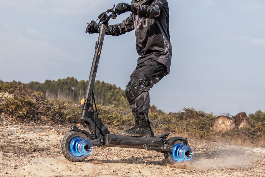 Rider in full protective gear lifting the front wheel of the Ausom L2 Max dual motor e-scooter on a dirt climb