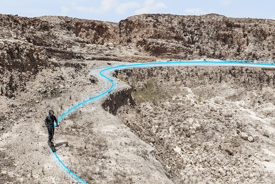 Aerial view of a rider tracing a long marked route through canyon terrain on the Ausom L2 Max electric scooter