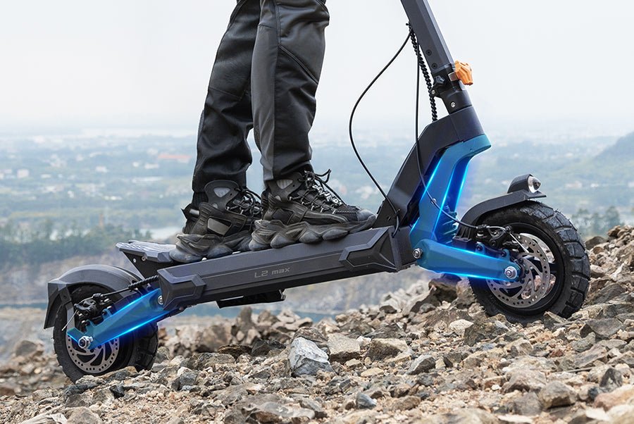 Ausom L2 Max electric scooter on rocky ground showing both swingarms under the deck