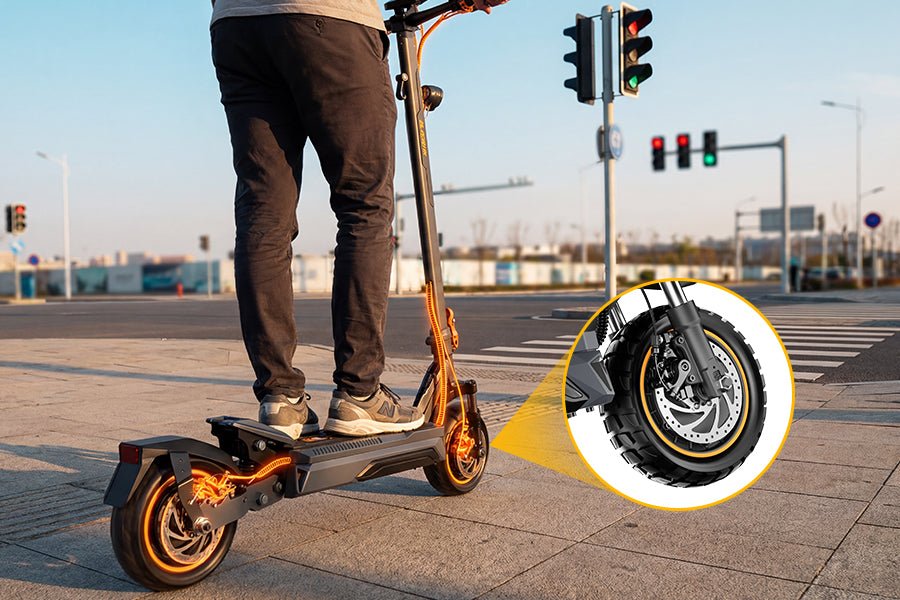 Rider stopped at a crosswalk on the Ausom K20 Pro dual motor e-scooter, with an inset of the front disc brake
