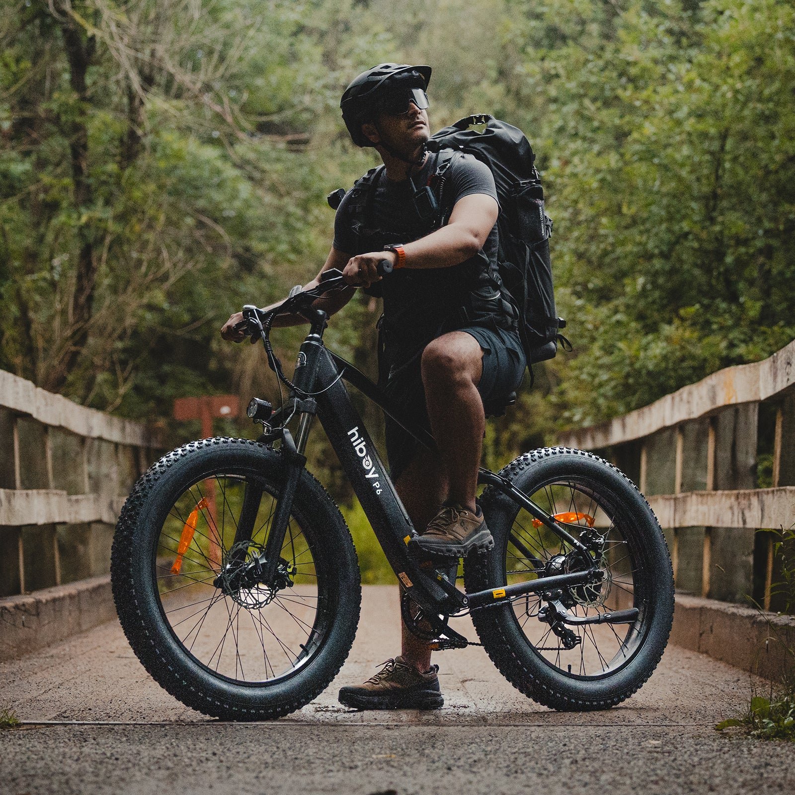 Rider with a backpack riding a Hiboy P6 fat tire electric bike up a rough hillside trail