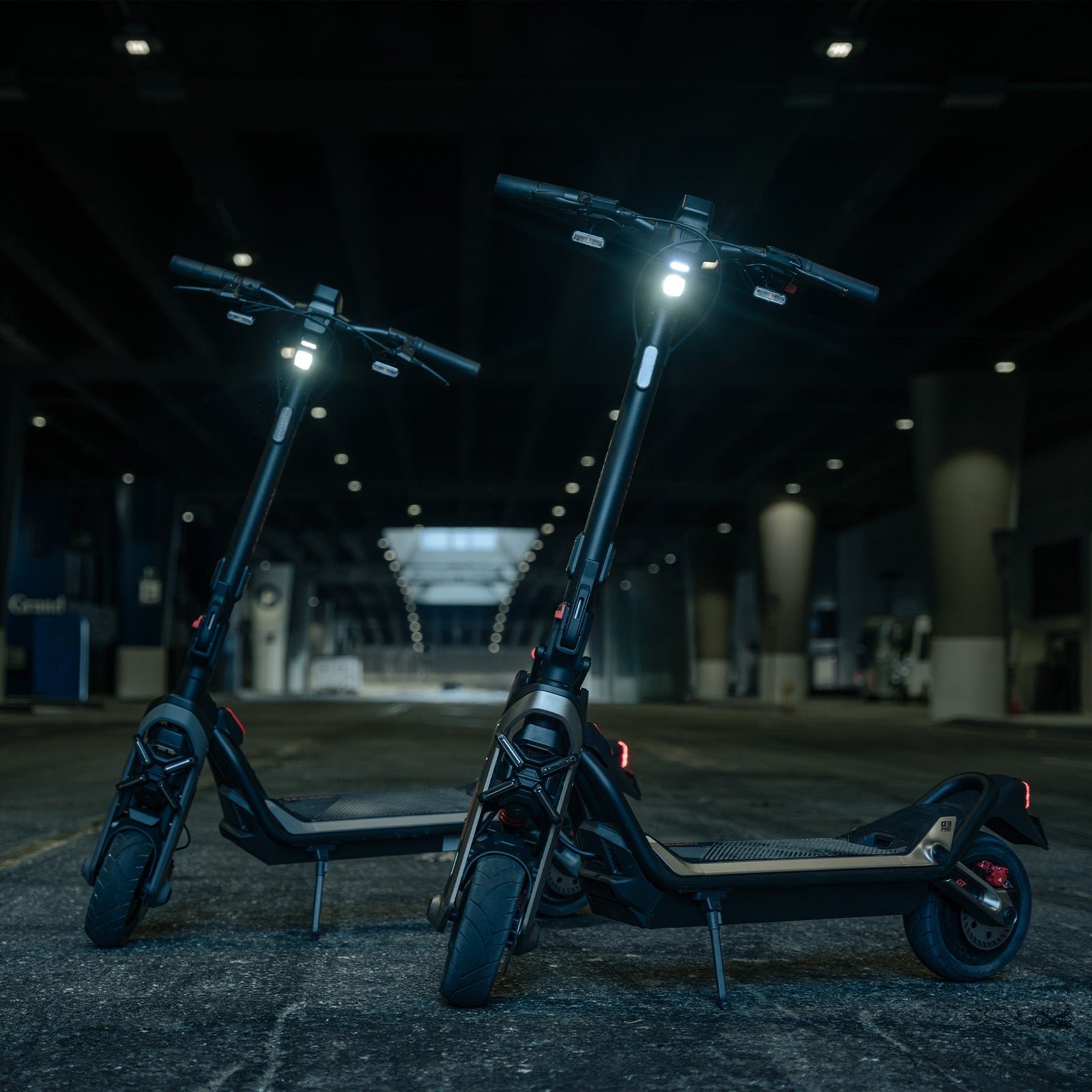 Two Segway GT3 SuperScooters parked at night with their headlights lit
