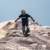 Rider descending a bare rock crest on an INMOTION V14 PRO electric unicycle