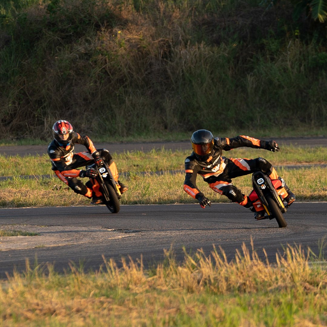 Two INMOTION P6 electric unicycle riders leaning through a corner in late evening light