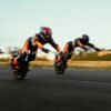 Two INMOTION P6 electric unicycle riders at speed, background blurred