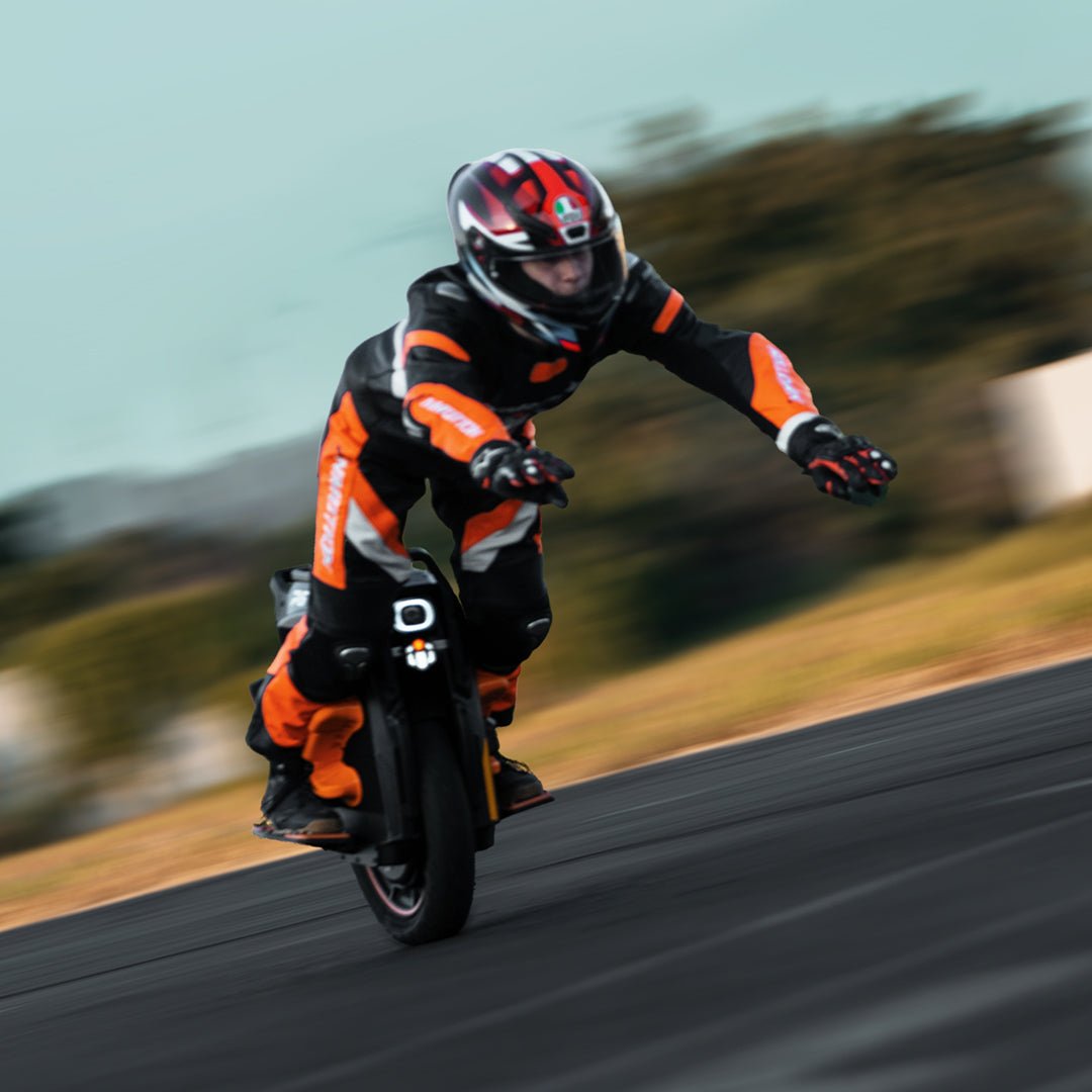 Rider crouched low on an INMOTION P6 electric unicycle on open tarmac