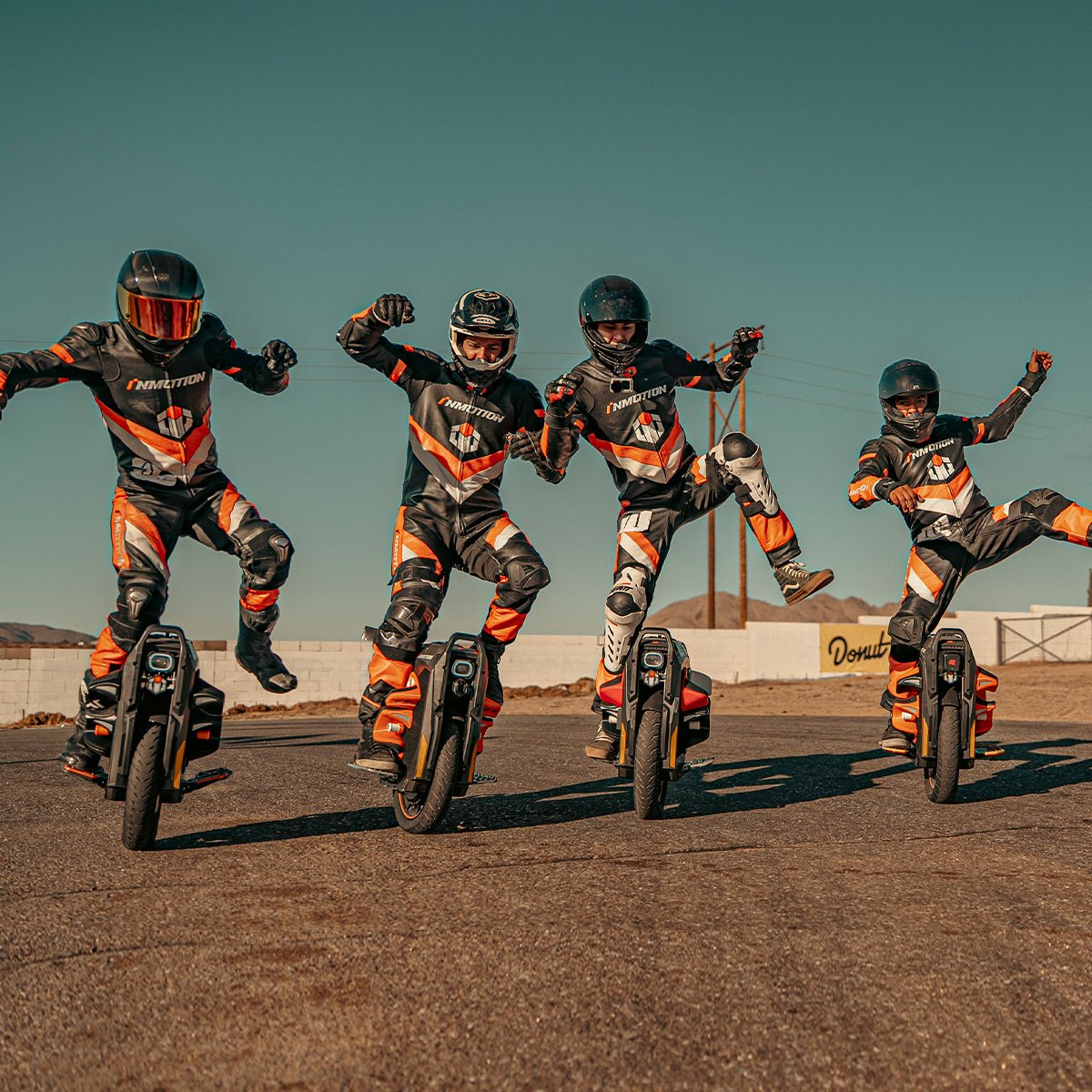 Four riders posing on INMOTION P6 electric unicycles in the desert