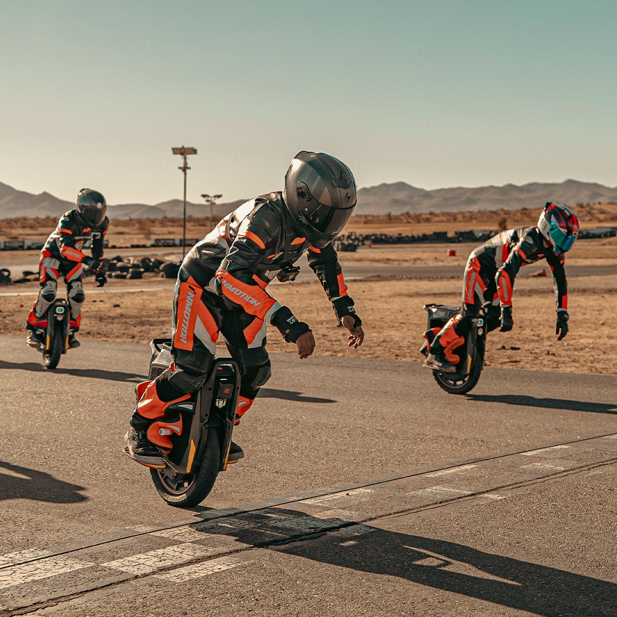Three INMOTION P6 electric unicycle riders on a desert airfield