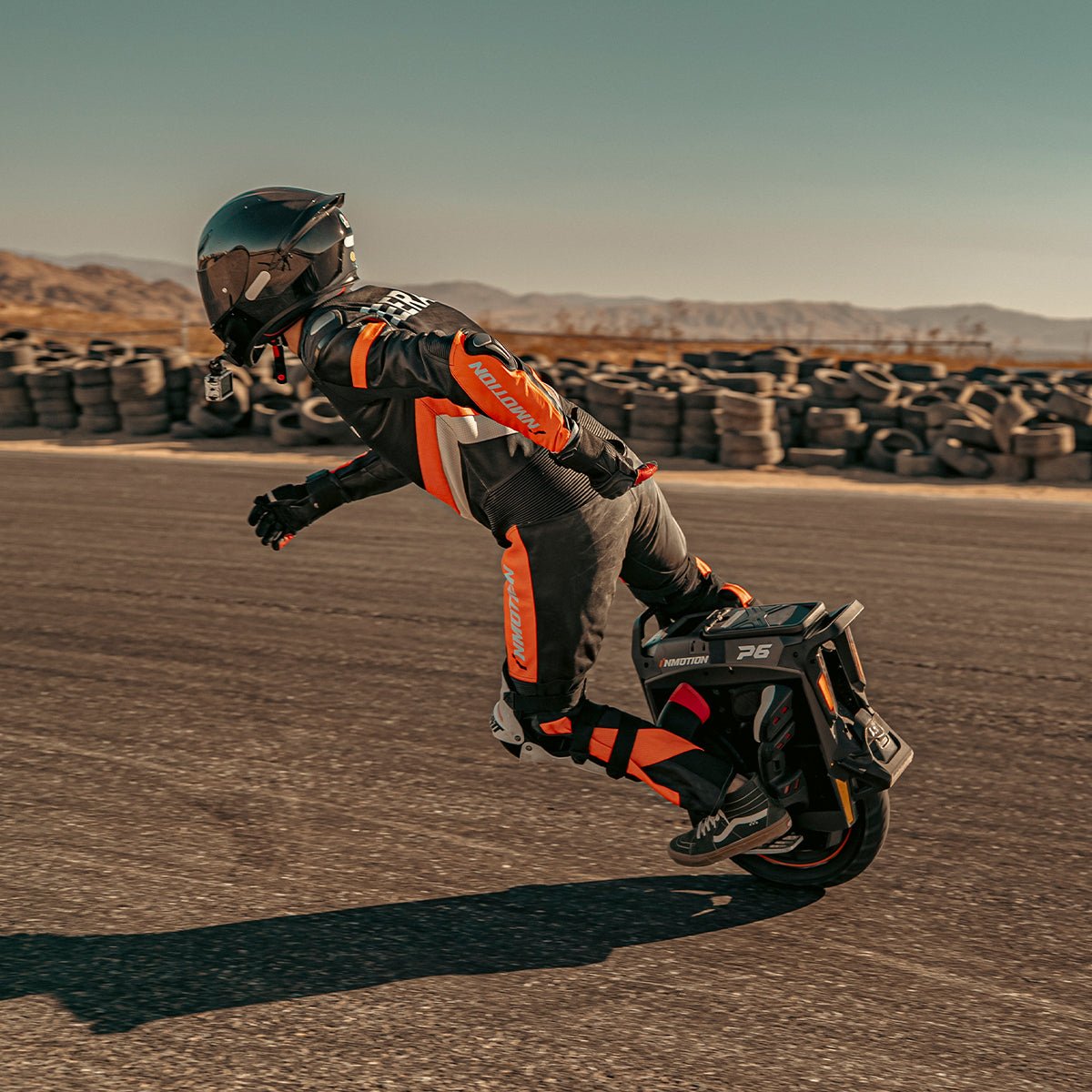 Rider carving an INMOTION P6 electric unicycle past a tyre wall