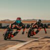 Two riders in leathers racing INMOTION P6 electric unicycles on a track