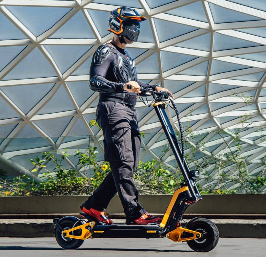 Rider on an INMOTION RS electric scooter beside a glass-panelled building