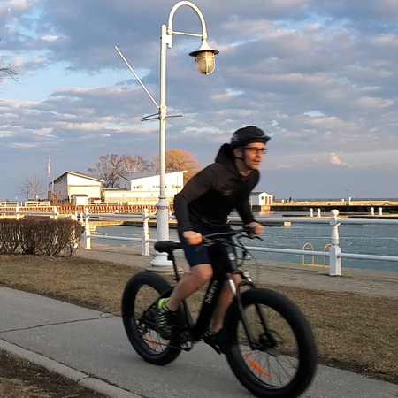 Rider on a Hiboy P6 fat tire electric bike along a harbor path