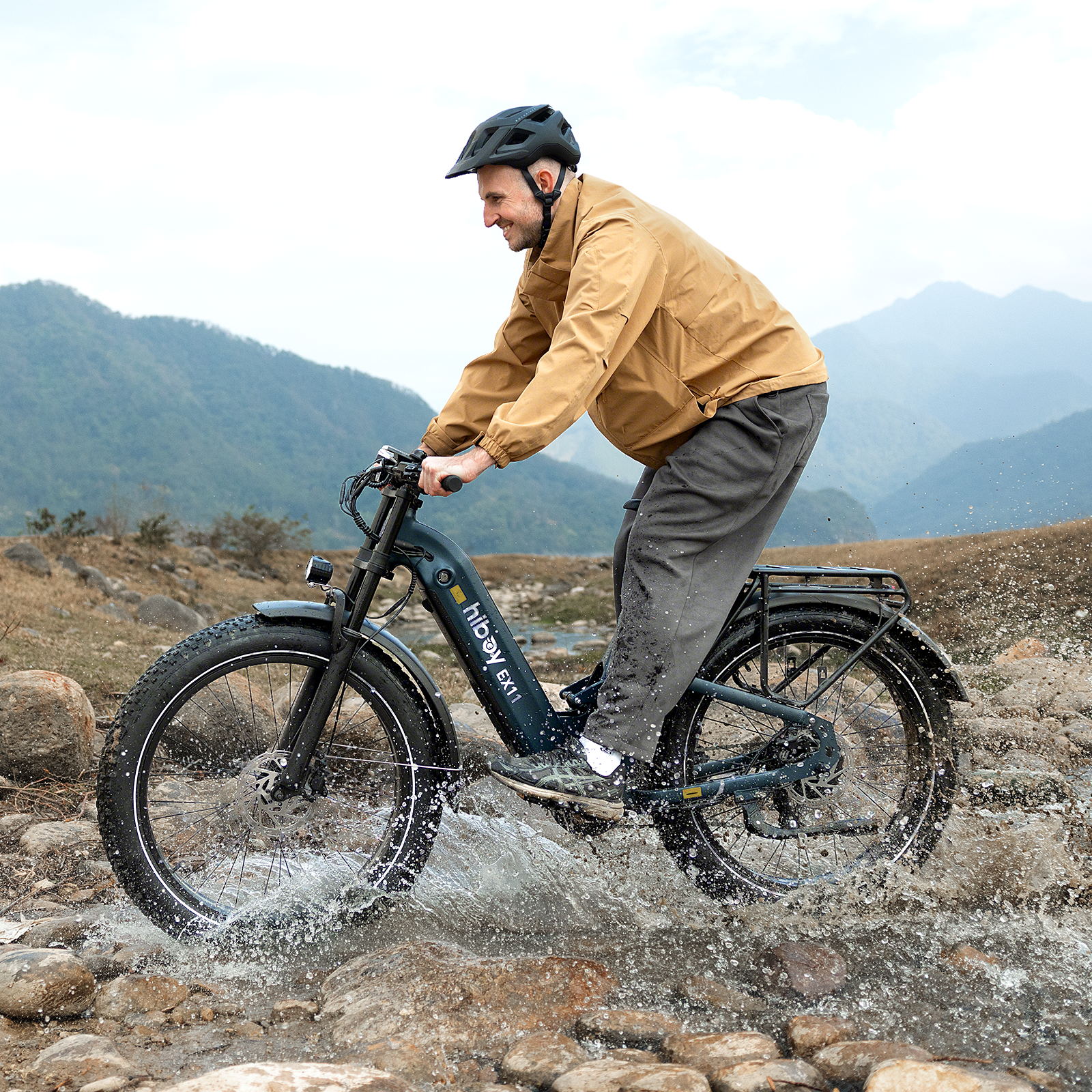 Rider on a Hiboy EX11 electric bike splashing across a rocky mountain stream
