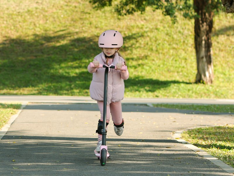 Child riding a pink Hiboy ES1 kids electric scooter along a park path
