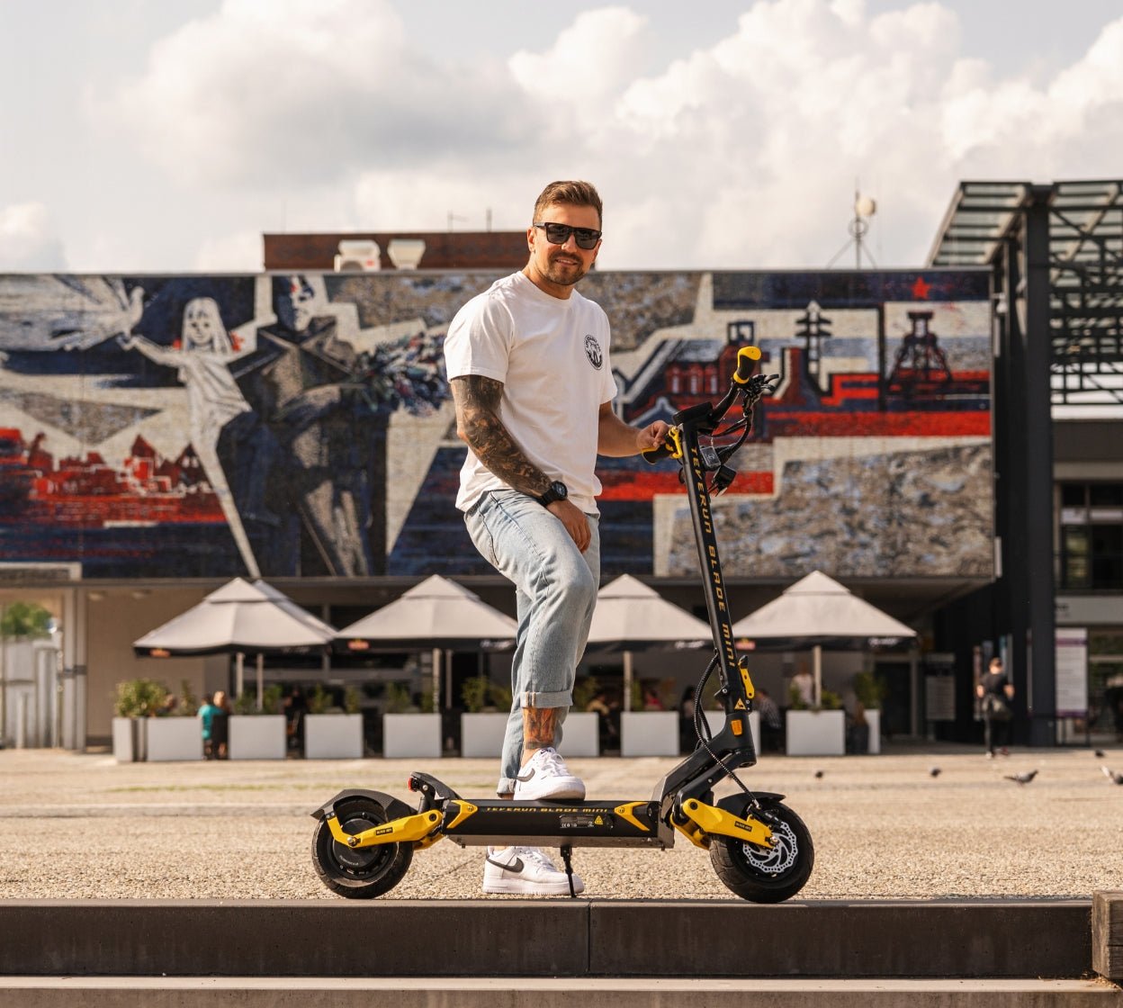 Rider standing with the Teverun Blade Mini Ultra electric scooter in a city square