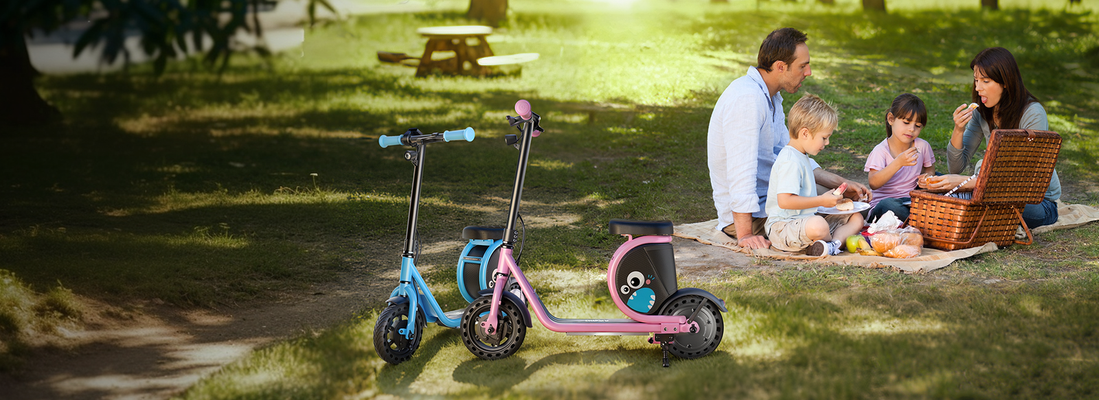 Blue and pink Hiboy Joy Haul kids electric scooters parked on grass beside a family picnic