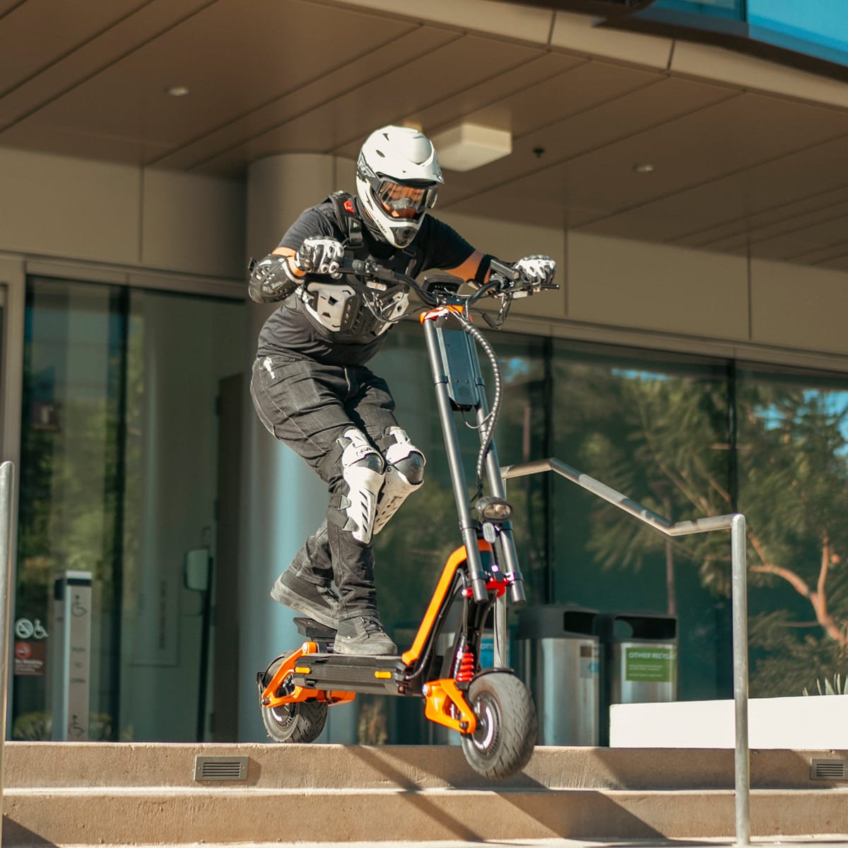 Rider landing an INMOTION RS Lite electric scooter off a set of steps outside a building