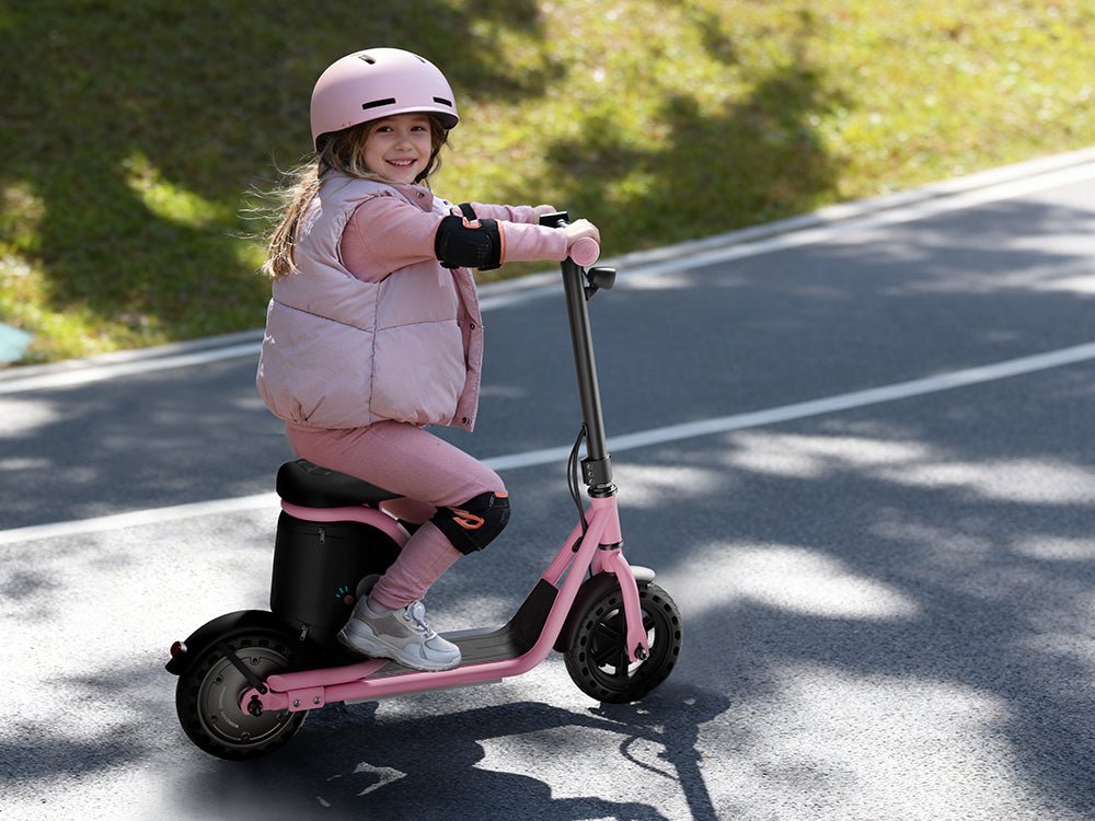 Child in a pink helmet seated on a pink Hiboy Joy Haul kids electric scooter on a road