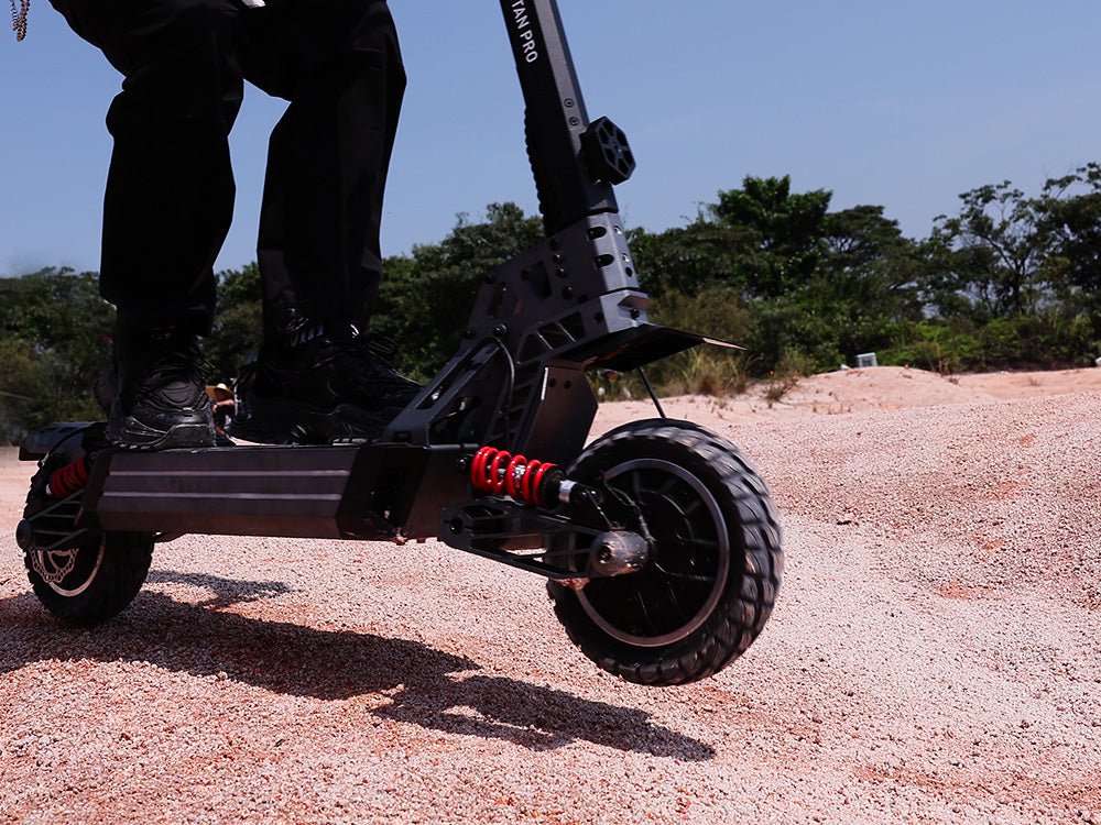 Rear suspension, red spring and hydraulic disc brake of the Hiboy TITAN PRO electric scooter on gravel