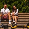 Two riders resting with their Teverun Blade Mini Ultra electric scooters on a bench