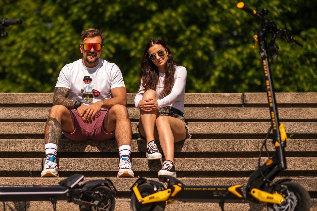 Two riders resting with their Teverun Blade Mini Ultra electric scooters on a bench