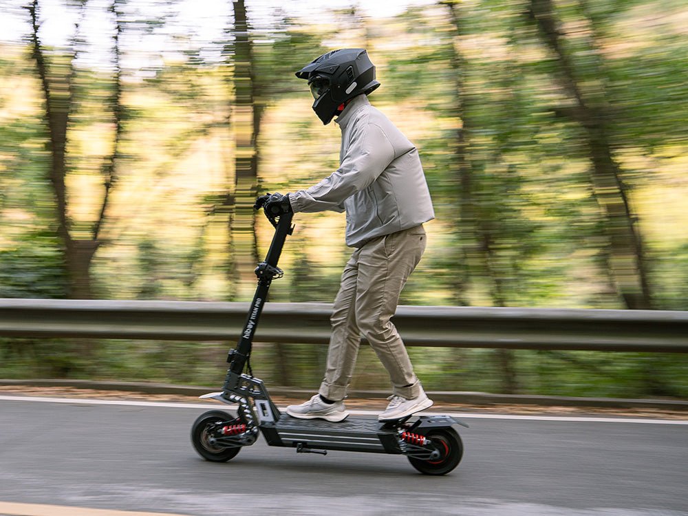 Rider in a full-face helmet on the Hiboy TITAN PRO electric scooter speeding along a forest road