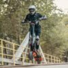 Rider lifting the front wheel of an INMOTION RS Lite electric scooter on a bridge