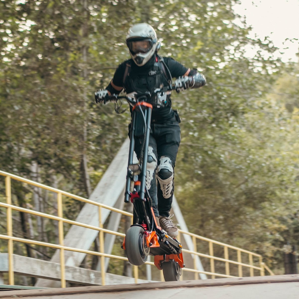 Rider lifting the front wheel of an INMOTION RS Lite electric scooter on a bridge