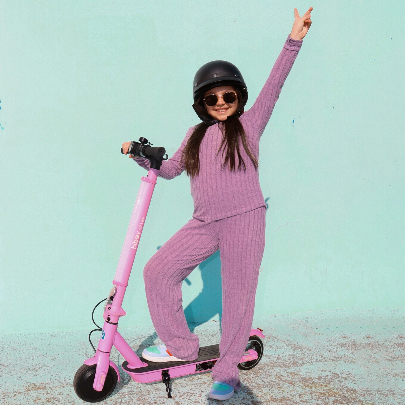Child in sunglasses and a helmet posing with a pink Hiboy S2 Lite electric scooter