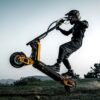 Rider pulling the front wheel of an INMOTION RS electric scooter up on a grass bank
