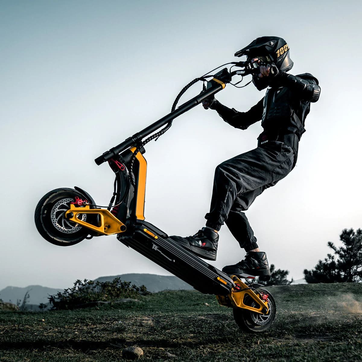 Rider pulling the front wheel of an INMOTION RS electric scooter up on a grass bank