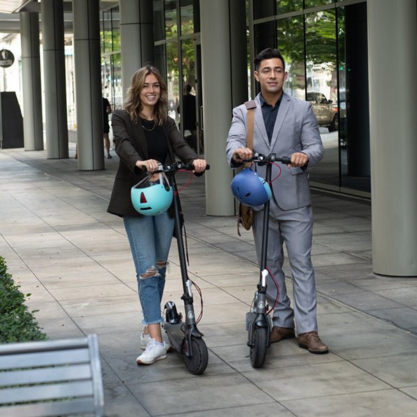 Two commuters standing with their Hiboy S2 electric scooters outside an office building