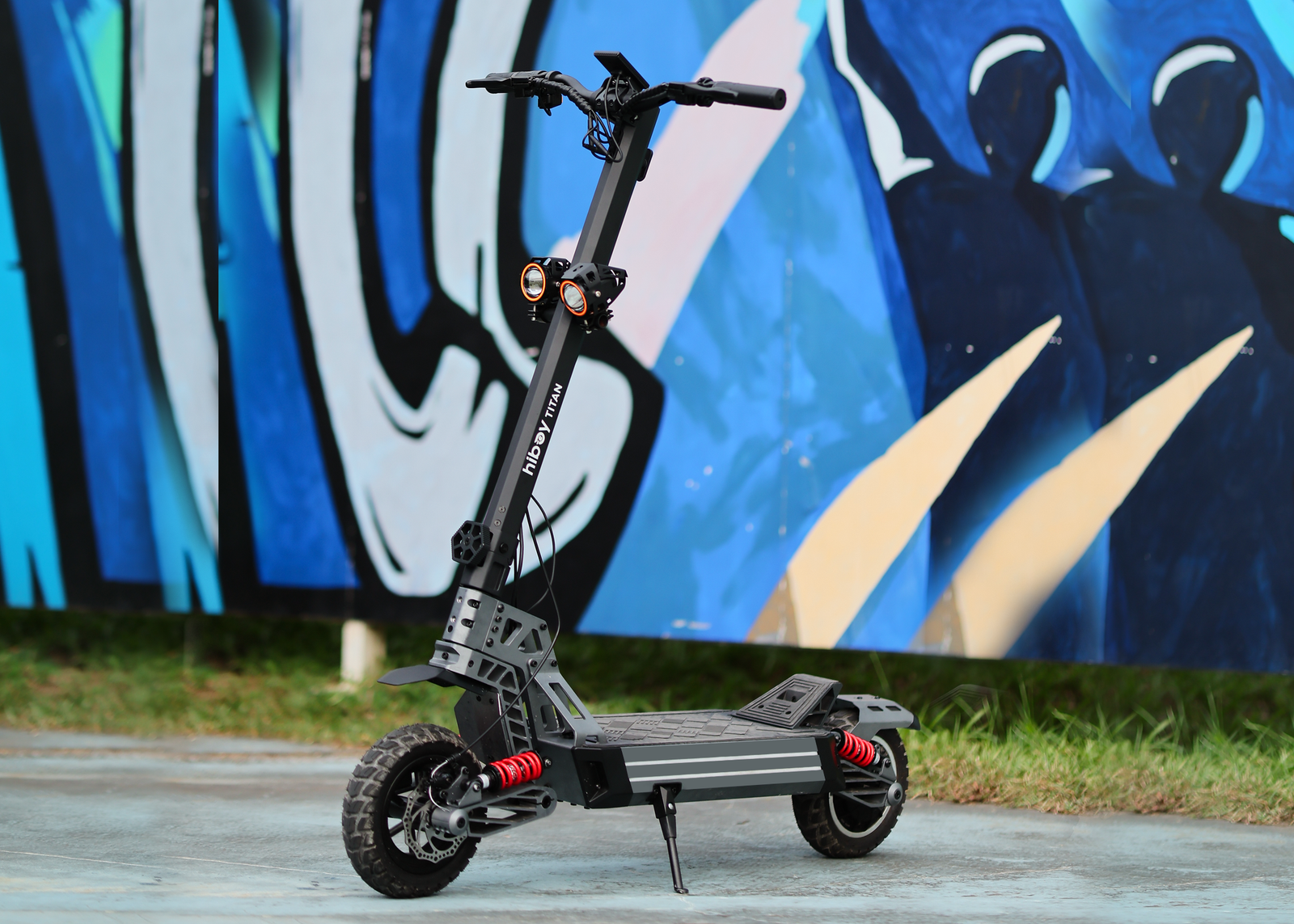 Hiboy TITAN electric scooter with twin headlights parked in front of a blue graffiti mural