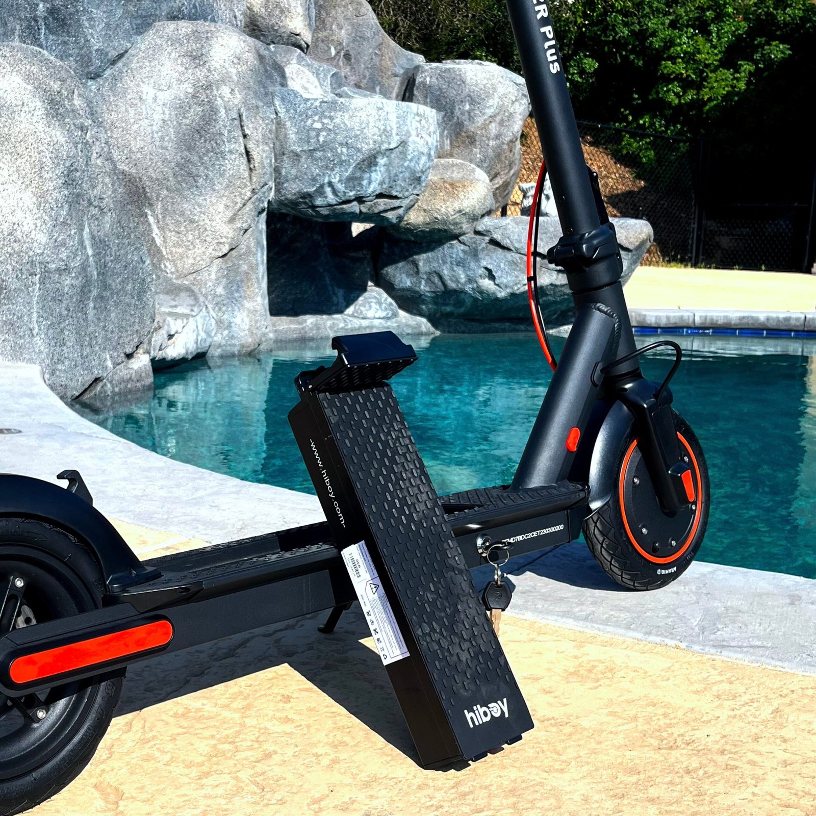 Hiboy S2R Plus electric scooter poolside with its removable battery lifted out of the deck