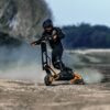 Rider throwing up dust on an INMOTION RS electric scooter on a gravel track