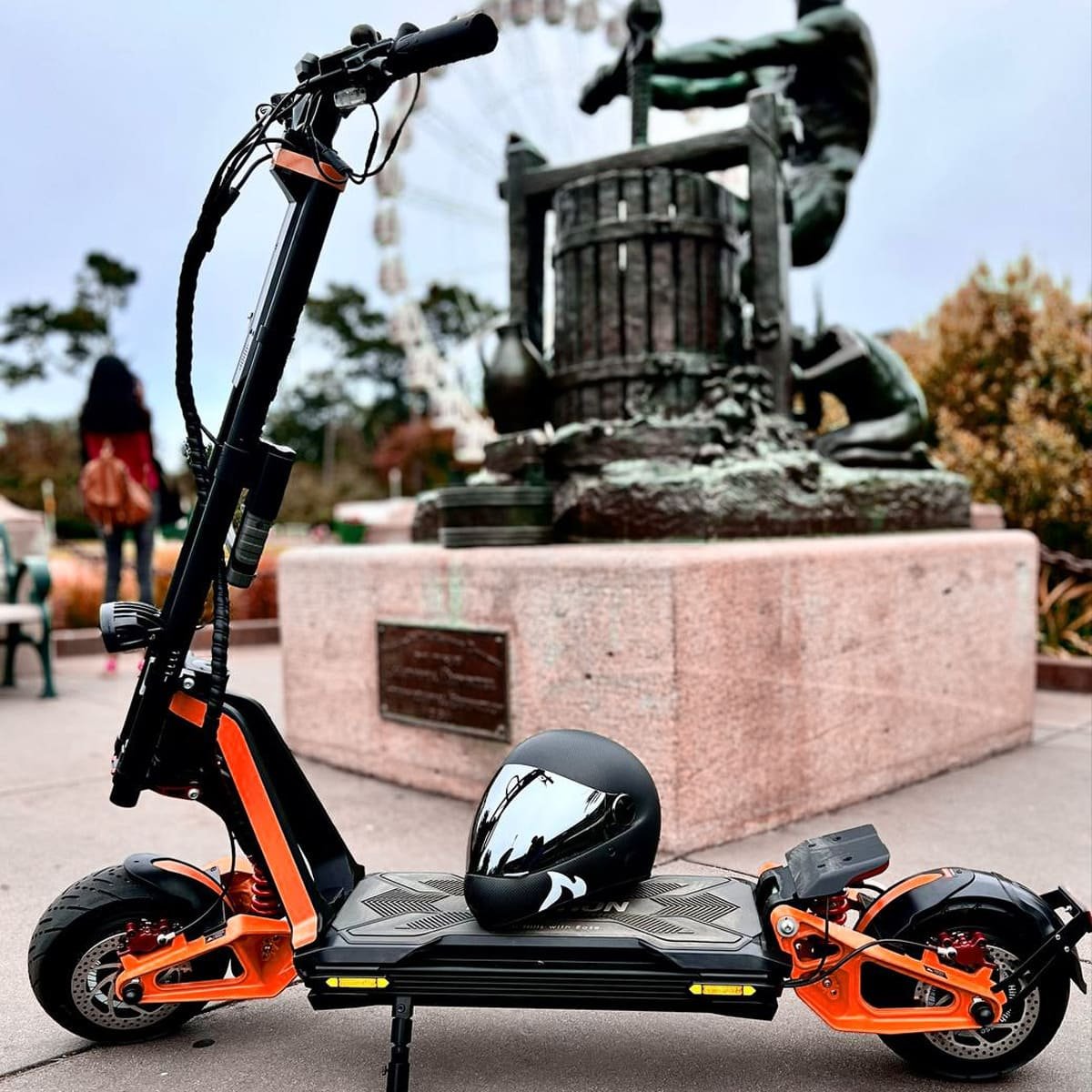 INMOTION RS Lite electric scooter parked in a plaza with a helmet resting on the deck