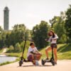Two riders resting with the Teverun Blade GT II electric scooter by the river