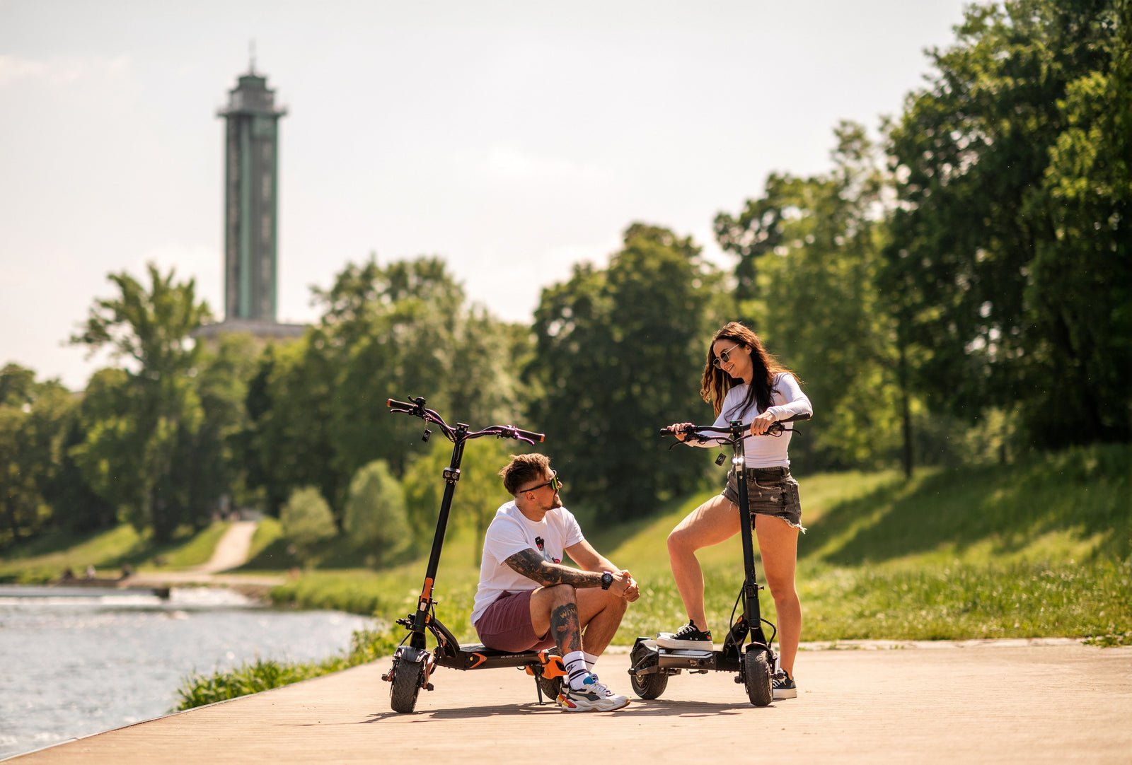 Two riders resting with the Teverun Blade GT II electric scooter by the river