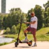 Rider standing with the Teverun Blade GT II electric scooter on the waterfront