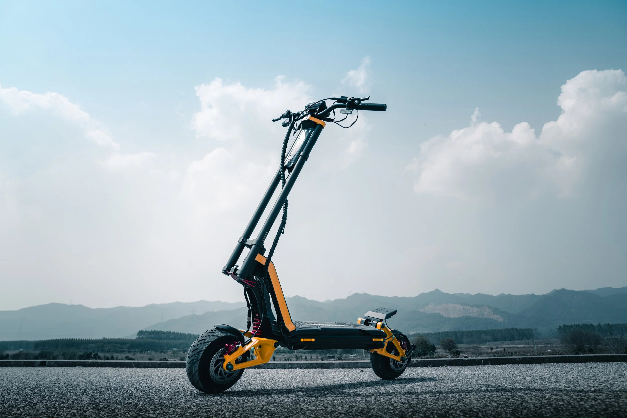 INMOTION RS electric scooter in profile on an open road with mountains behind