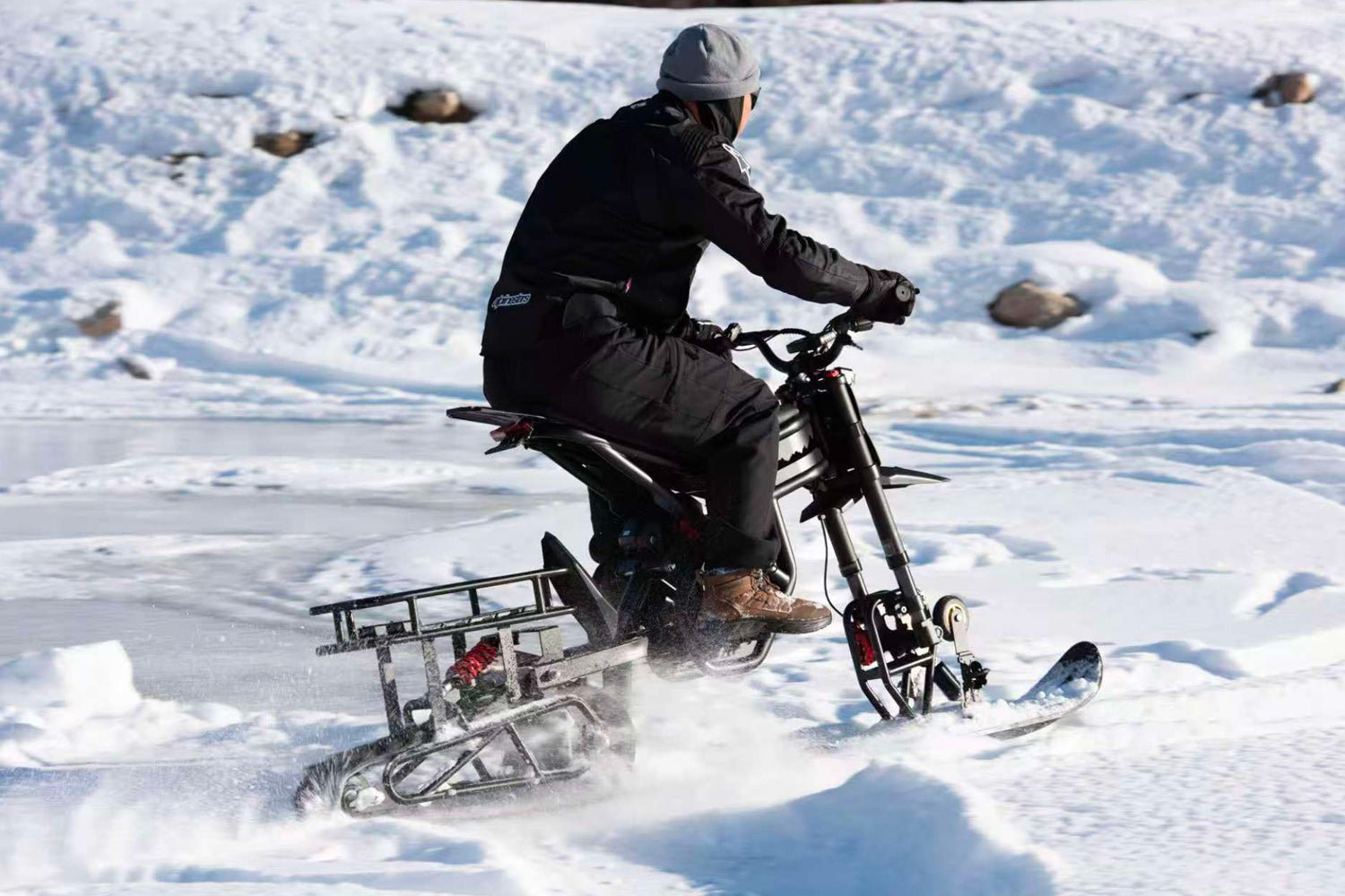 Rider crossing a frozen field on a Riding’times electric motorbike with the snow track kit