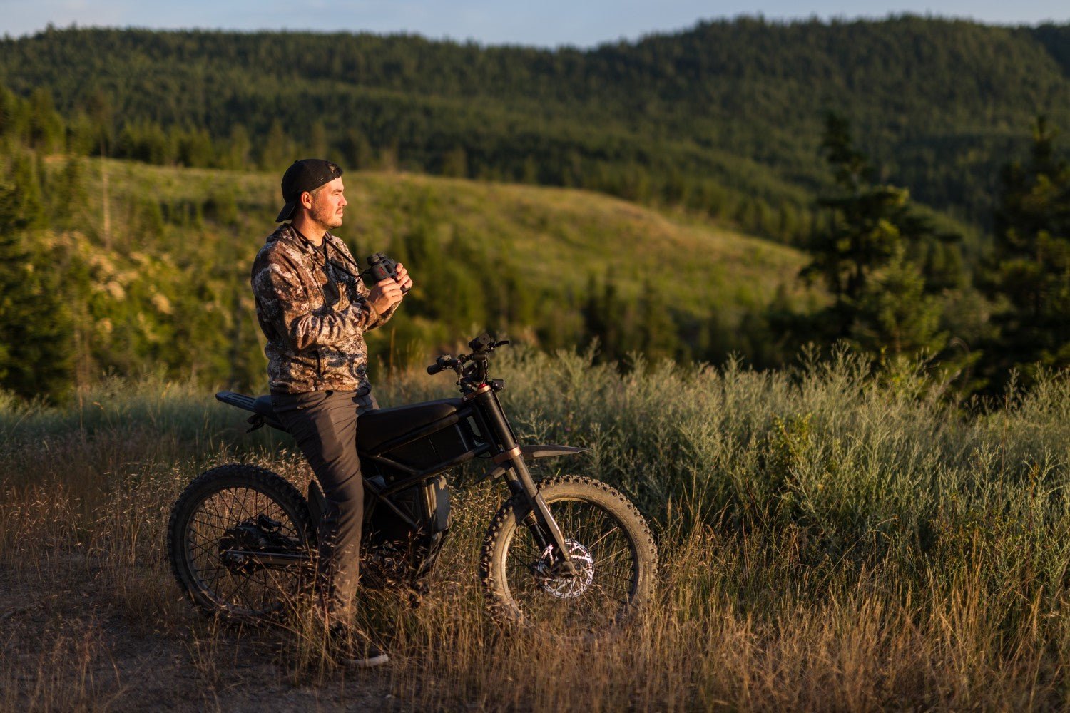 Rider standing beside the Riding’times GT73 Pro electric motorbike on a hillside at dusk